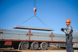 The builder controls the unloading of the panels for the roof of the house with a crane.